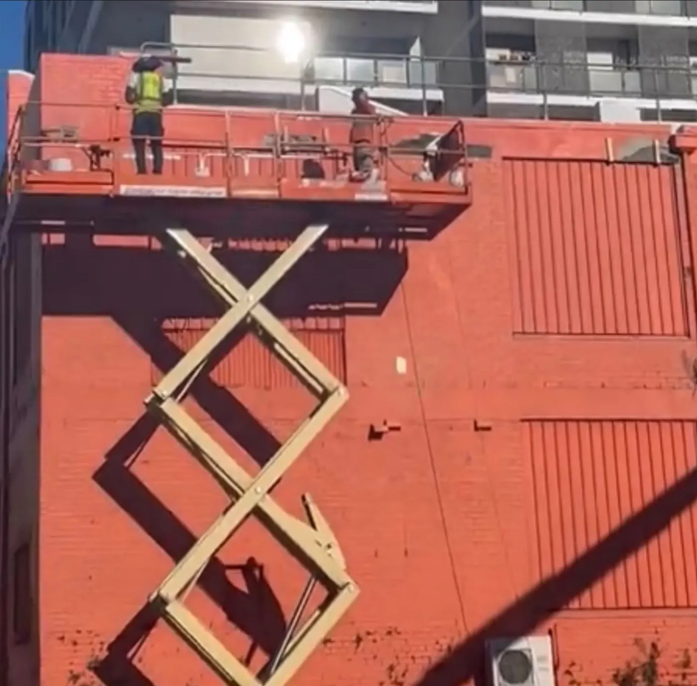 Brick repointing from a scissor lift on a painted brick commercial building