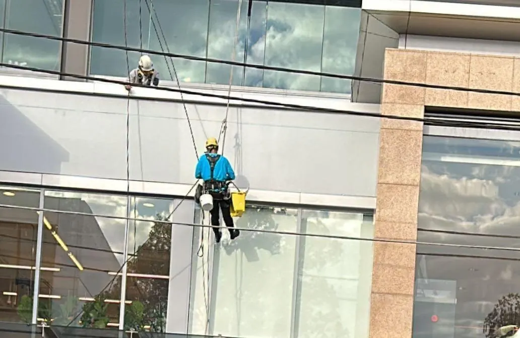 Commercial painting on rope: painter working on the façade of a showroom