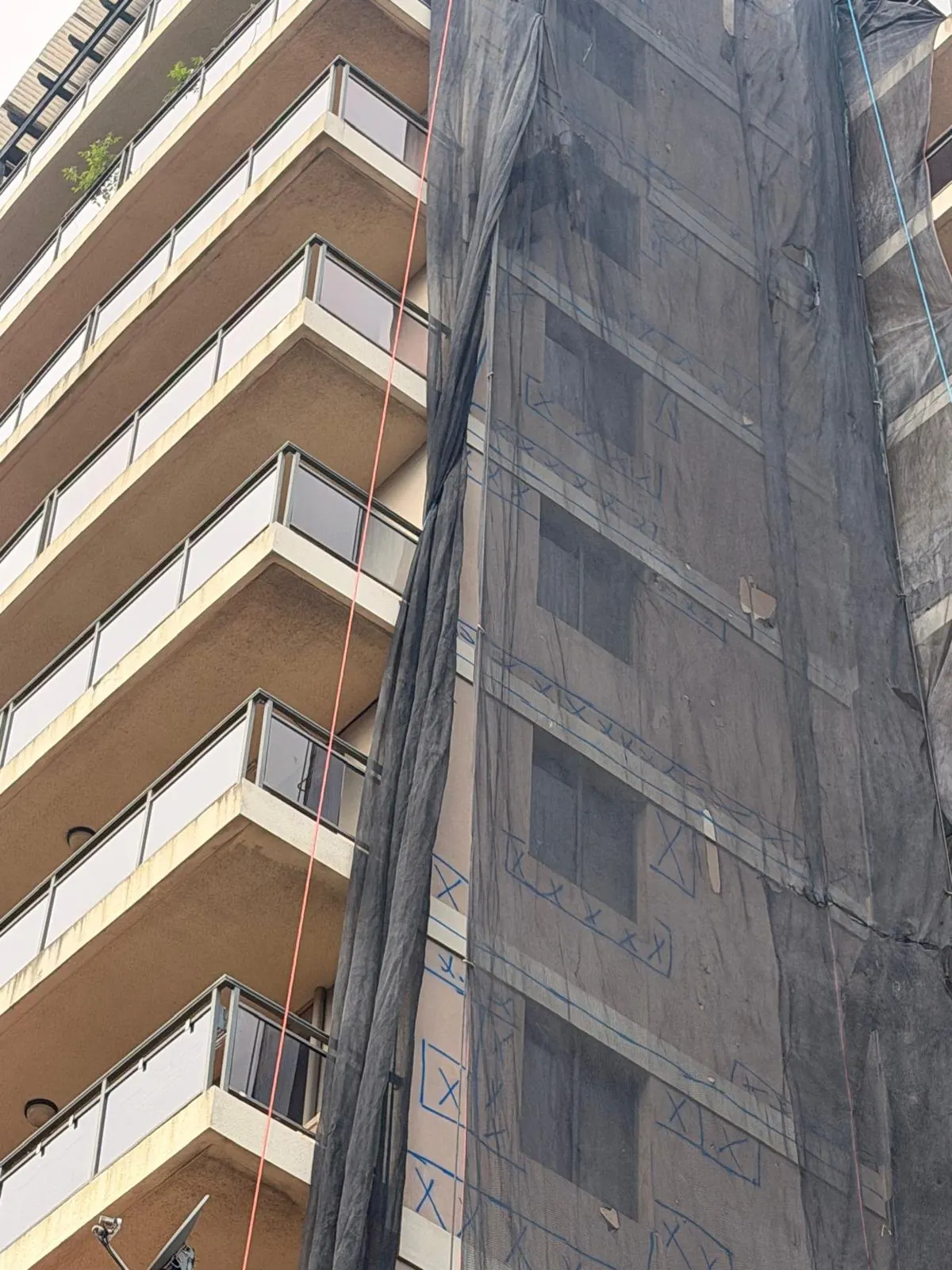 Concrete defects marked on a tower behind containment netting
