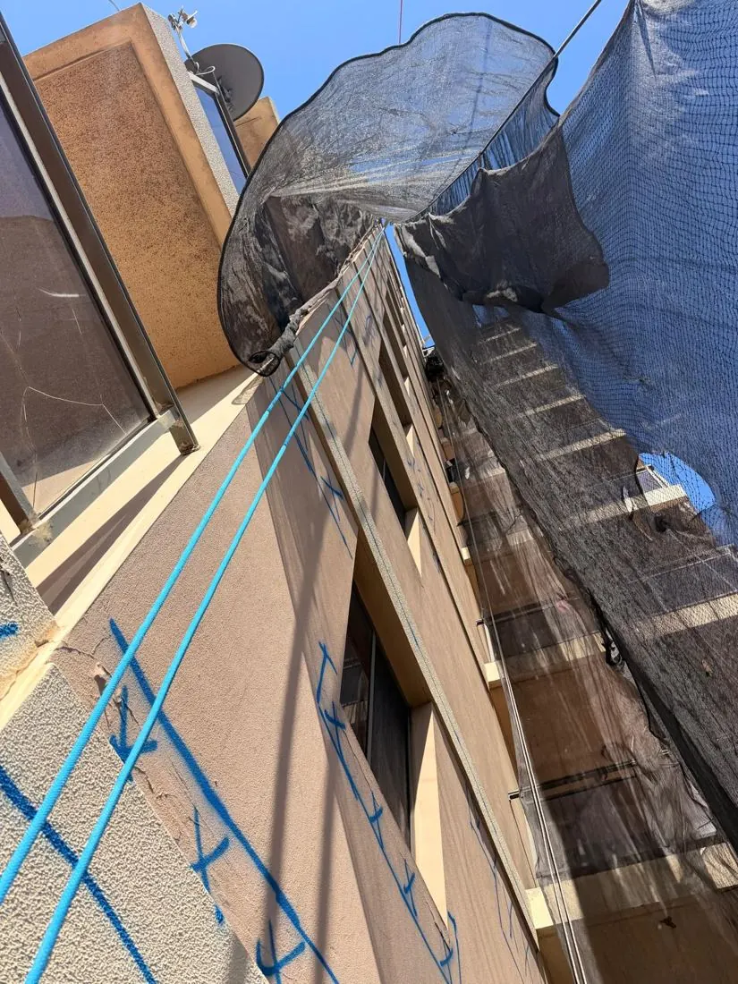 Containment netting rigged below rope access concrete repairs, seen from the base of the building