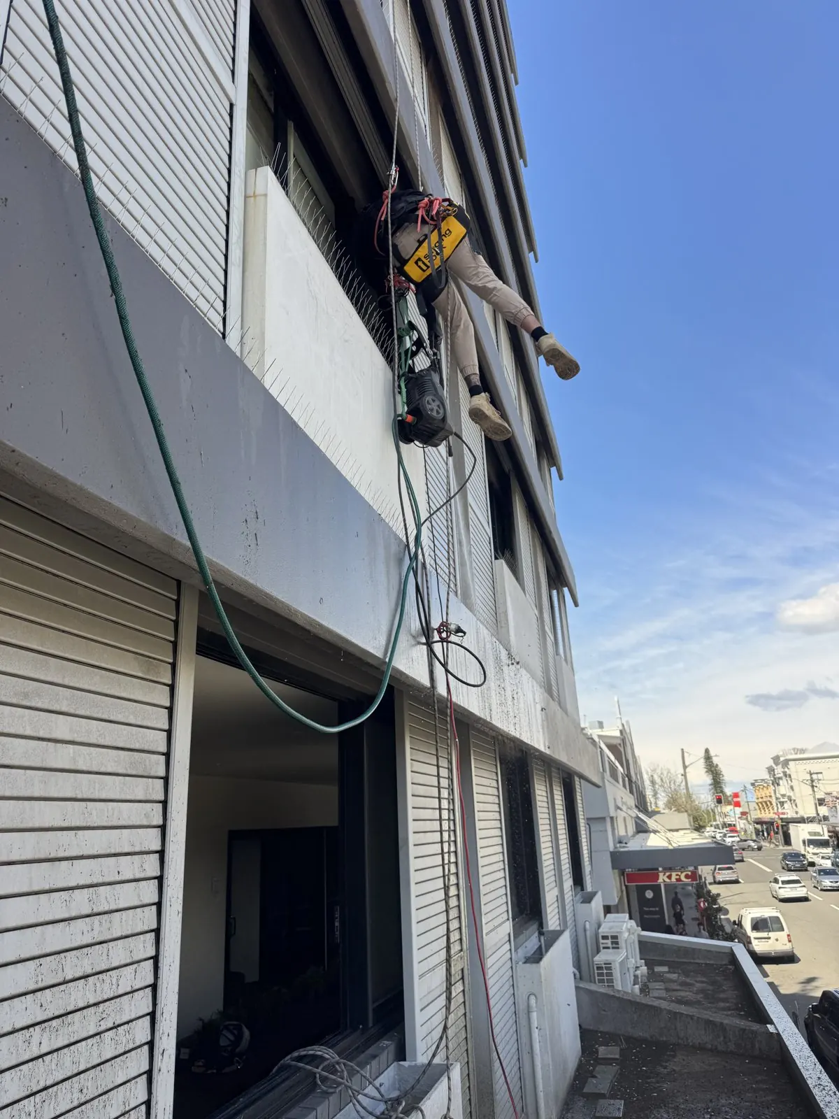 Technician on rope working down the louvred façade of a Randwick hotel