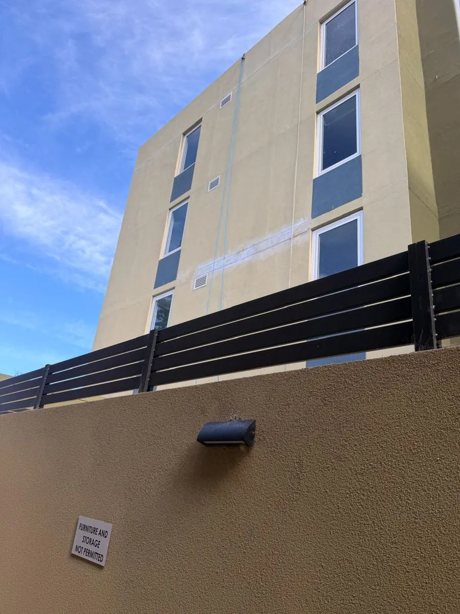 Mascot apartment building before rectification, with a pale band of failed render across the wall