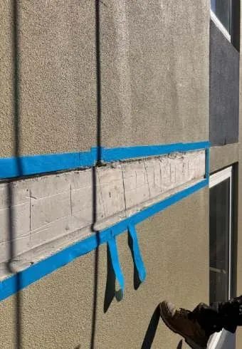 Deteriorated render cut out back to sound material and masked off, ready for repair