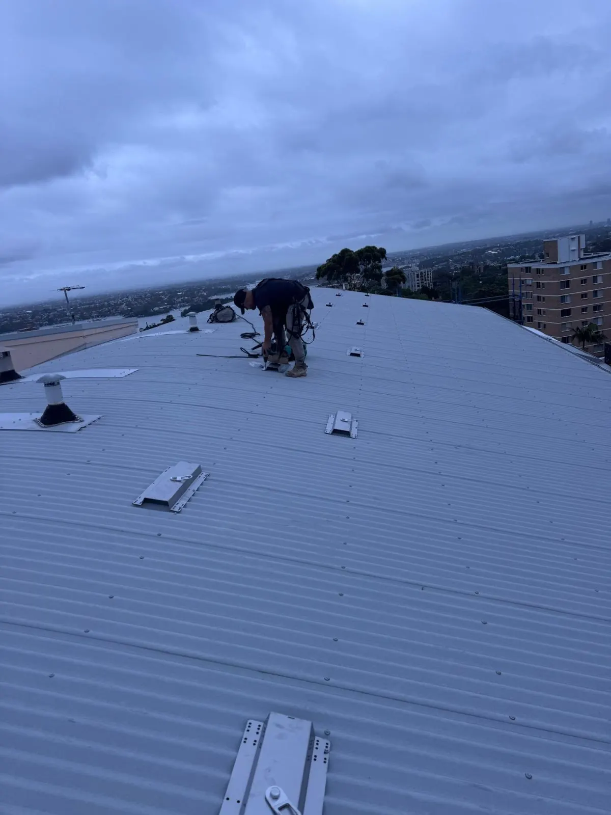 Anchor point installation: technician fixing roof anchors to a curved metal roof