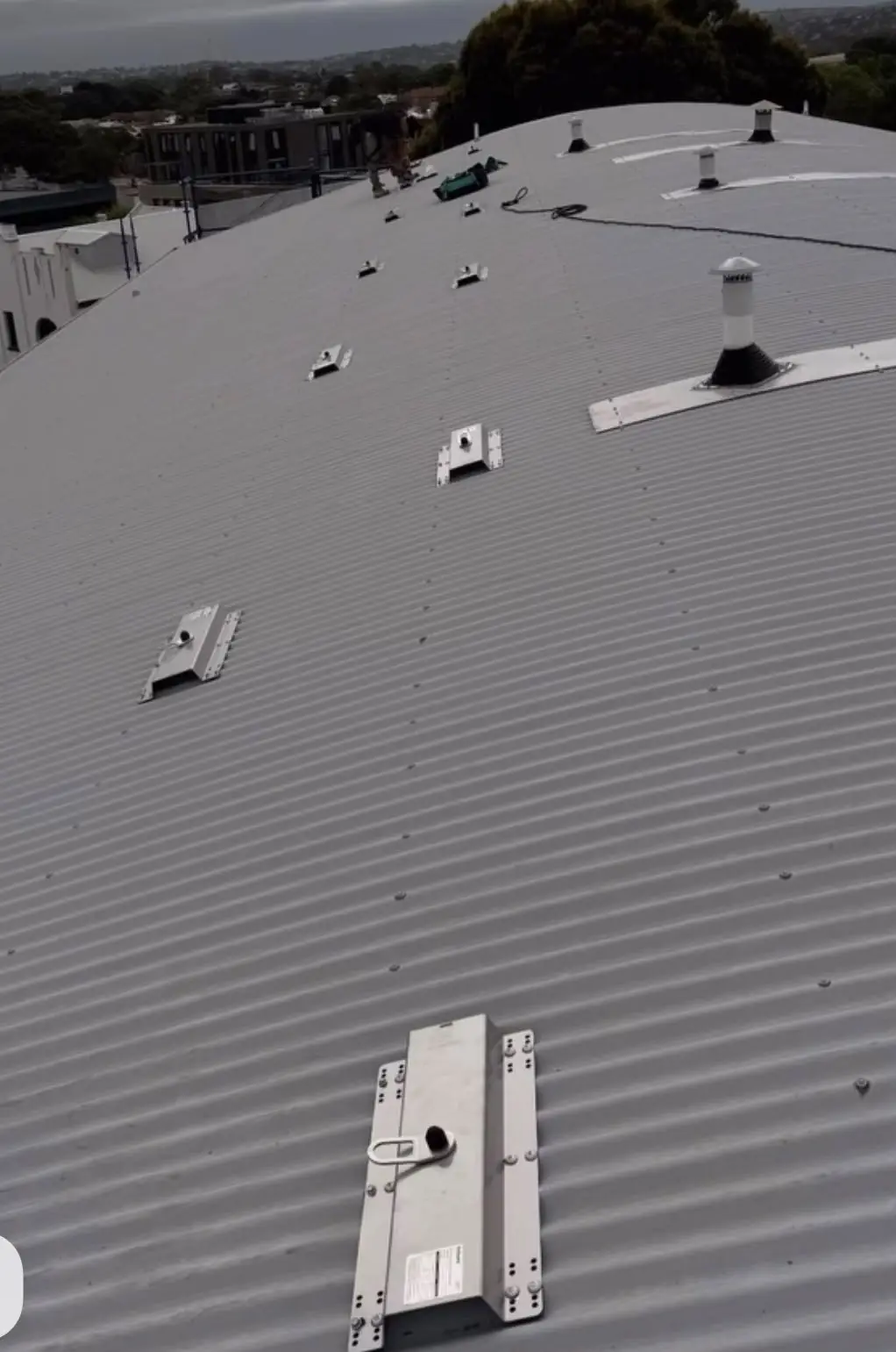Row of new roof anchor plates fixed to a curved metal roof in Sydney