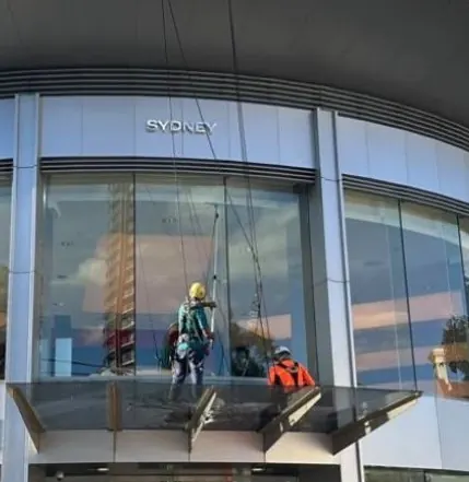 Commercial window cleaning: two technicians on rope cleaning the glass façade of a car showroom