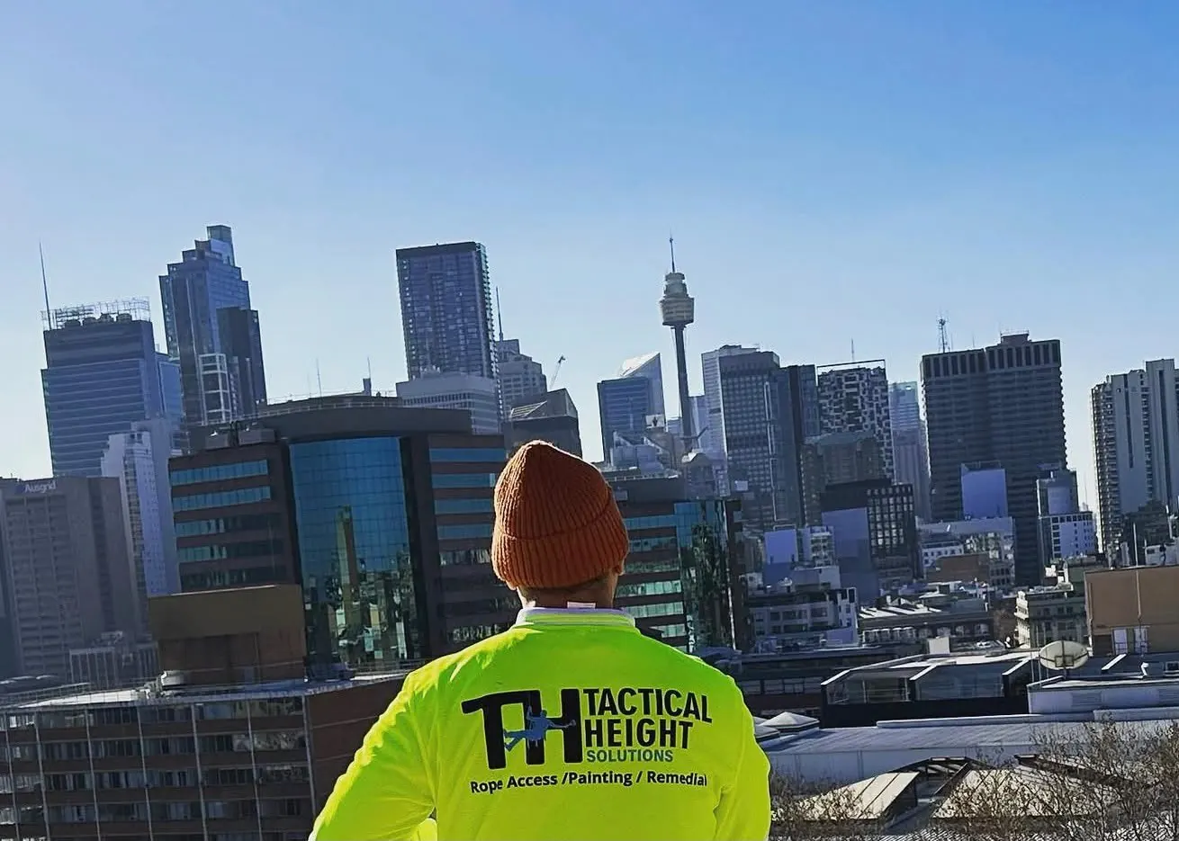 Tactical Height Solutions technician in a branded hi-vis shirt overlooking the Sydney skyline