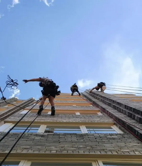 Three rope access technicians descending a Sydney apartment building