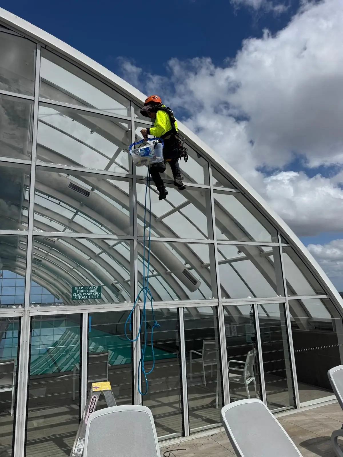 Technician on rope cleaning a curved glass roof